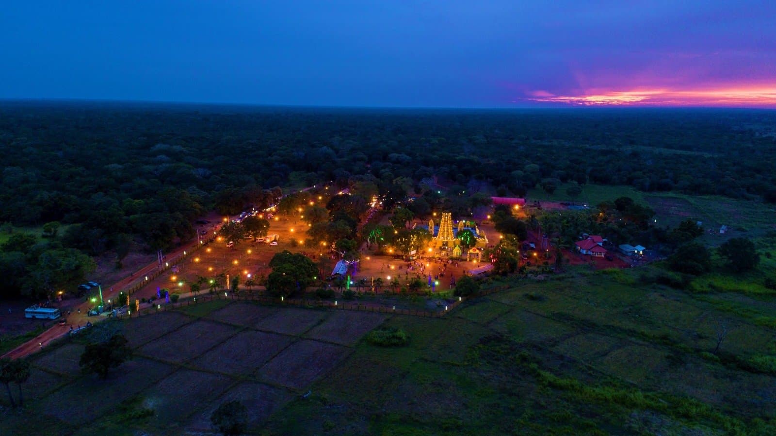 Aerial view of the illuminated temple at sunset with violet and orange skies